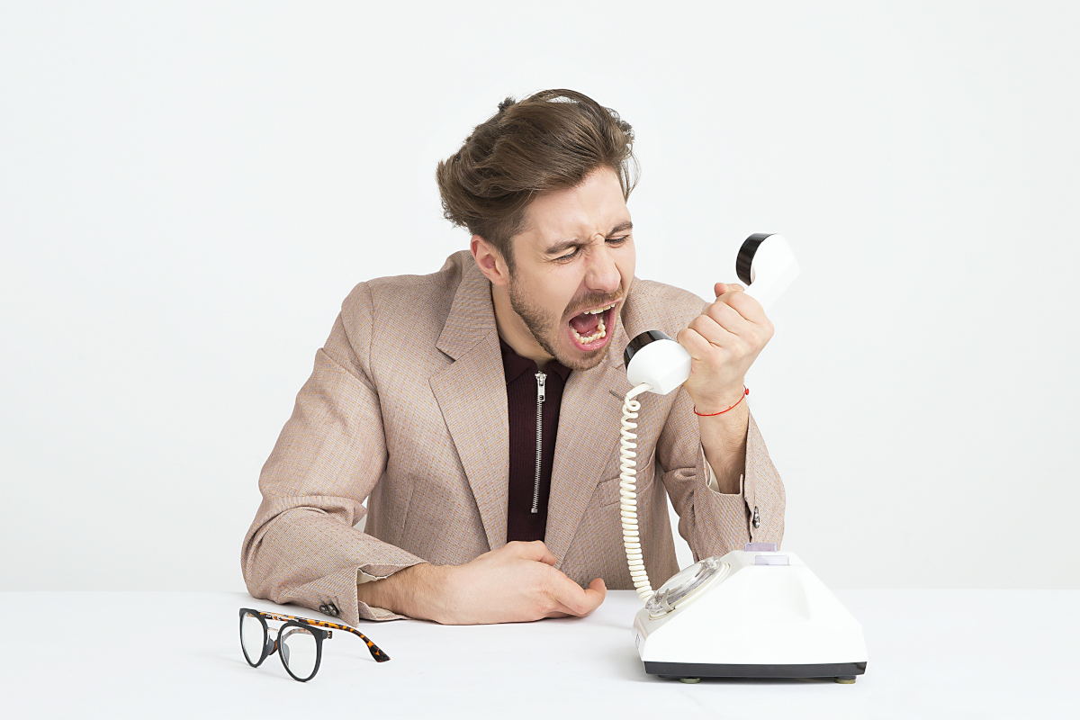 Homme criant à un téléphone fixe.